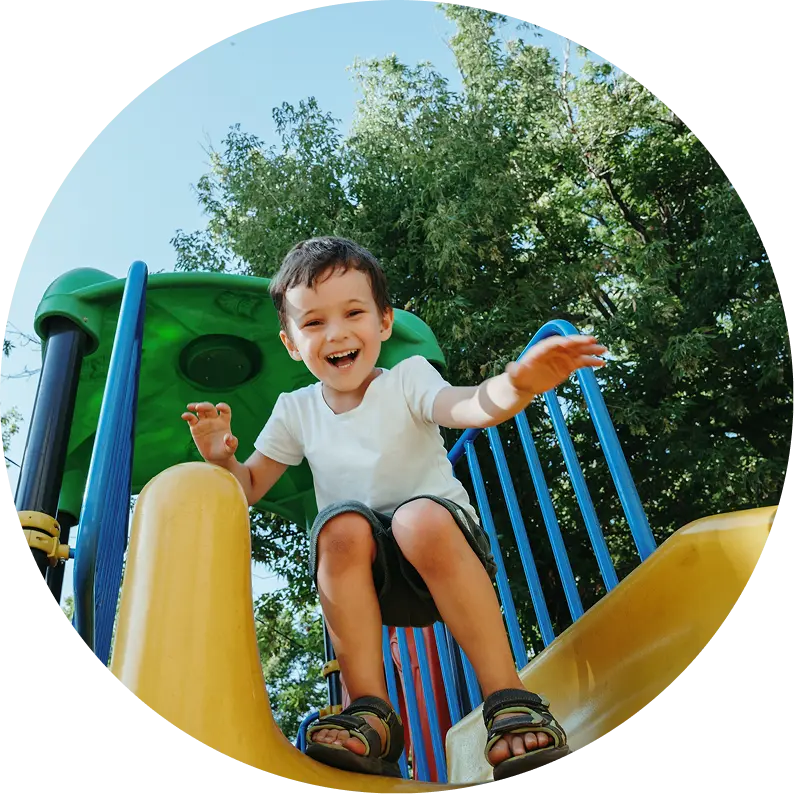 Child playing on the playset about to go down a slide.